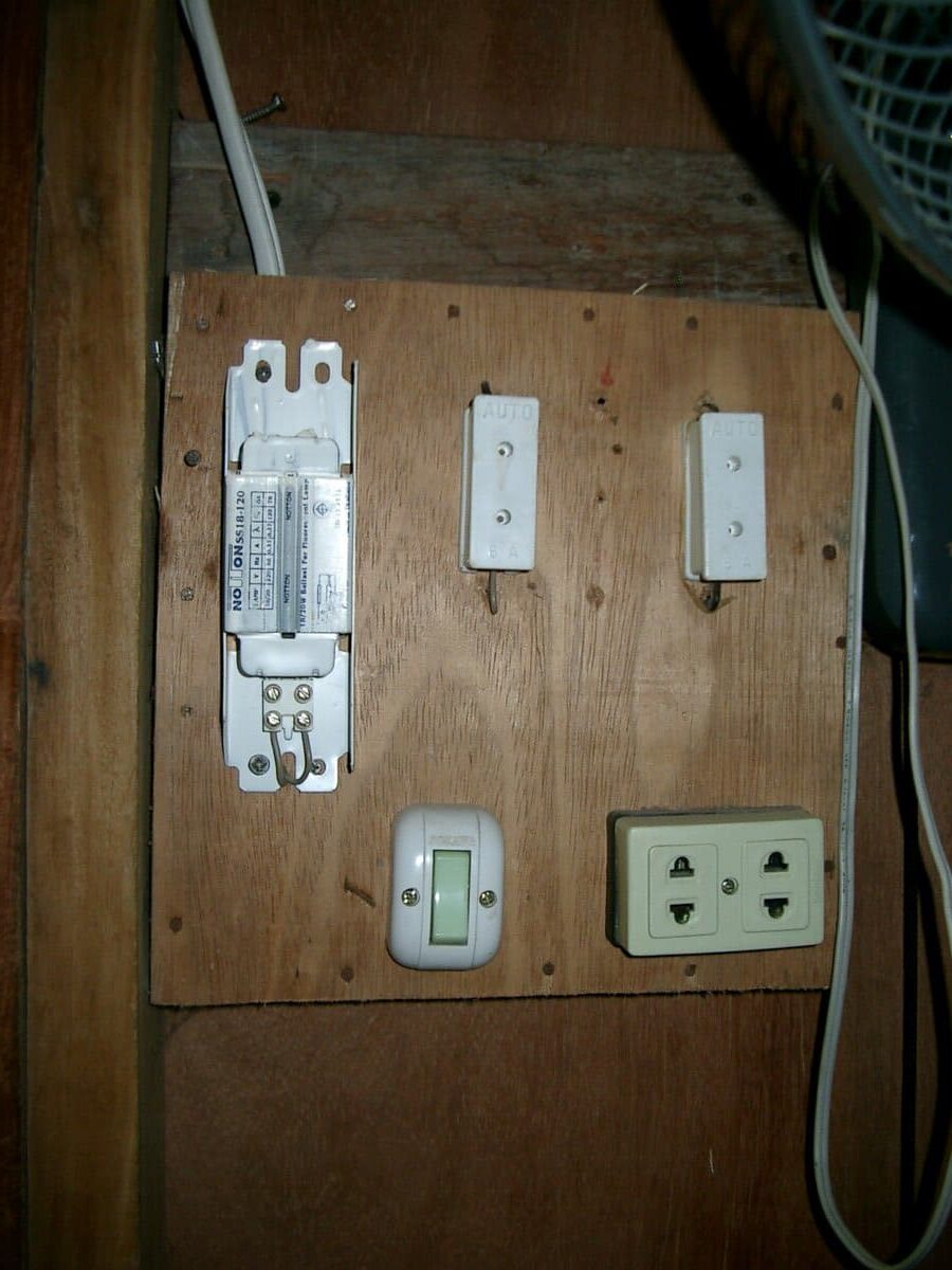 Ältere Elektroinstallation auf Holzplatte mit Sicherungen und Schaltern