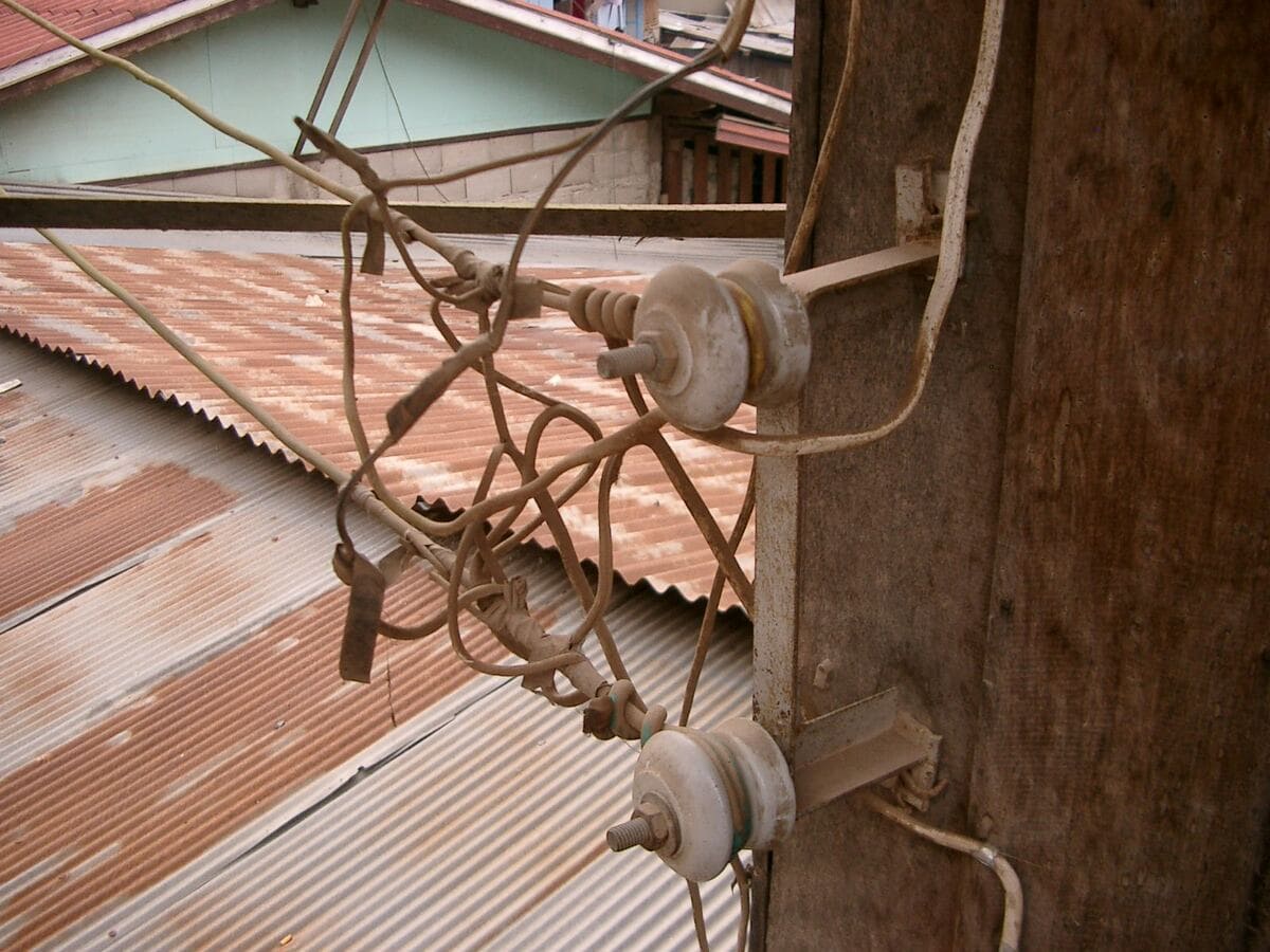 Freiliegende Leitungen und Isolatoren an einem Holzmast