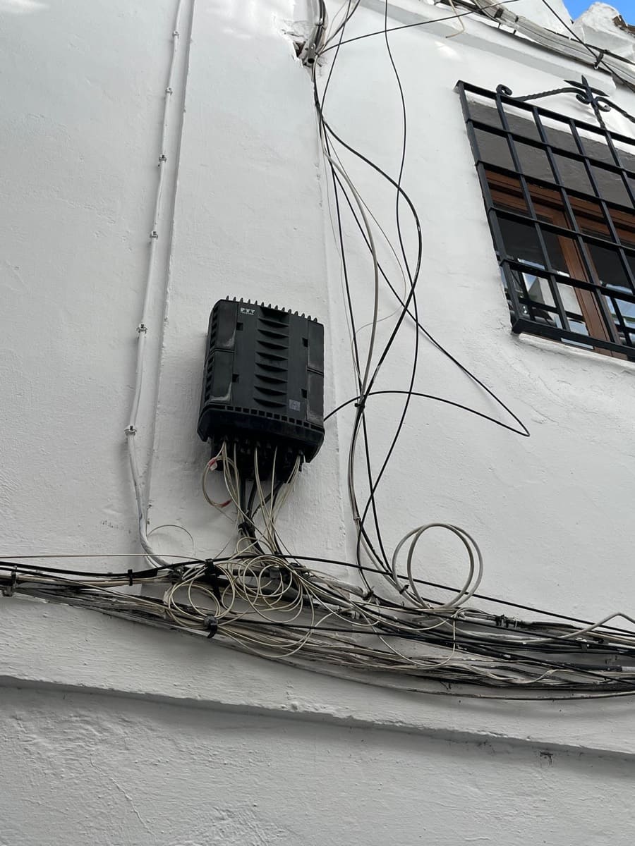 Kabelbündel und Anschlusskasten an weißer Hausfassade